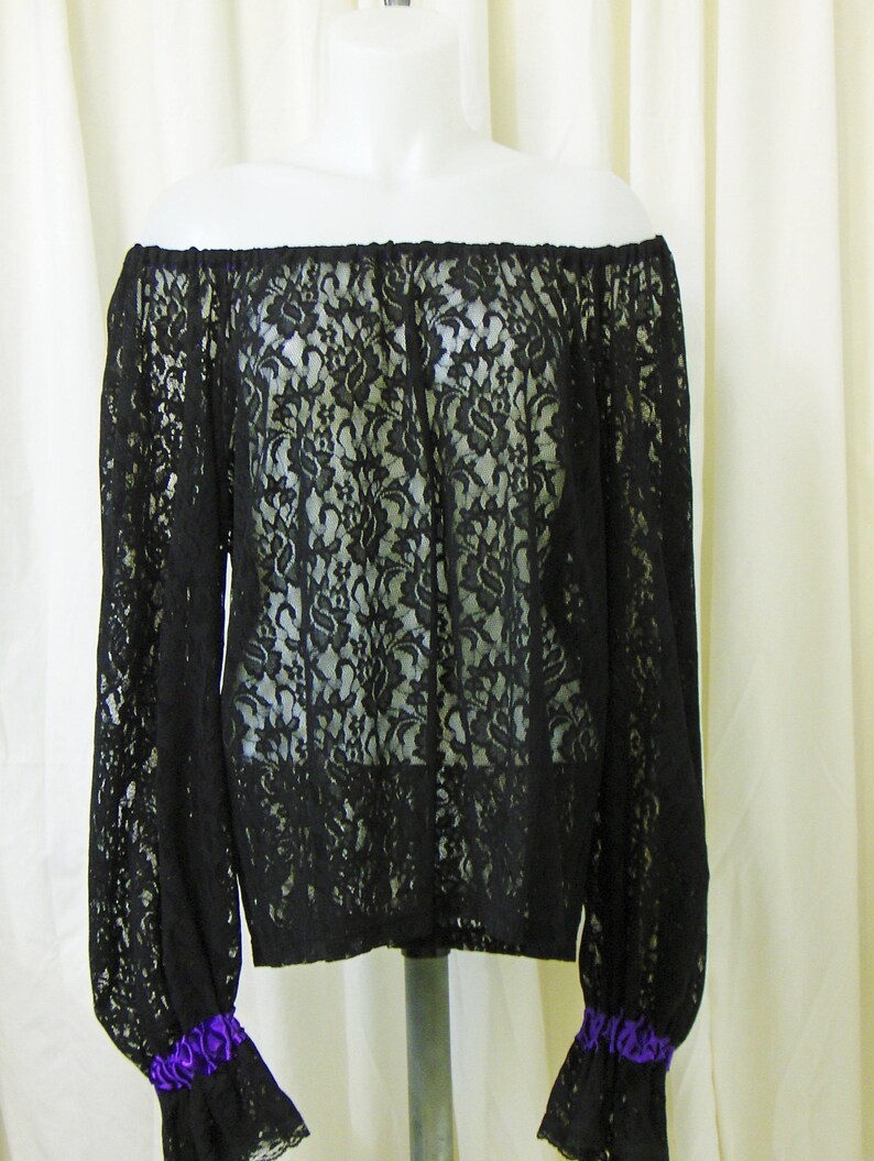 May include: Black off-the-shoulder lace top with long sleeves and purple ribbon trim at the cuffs.