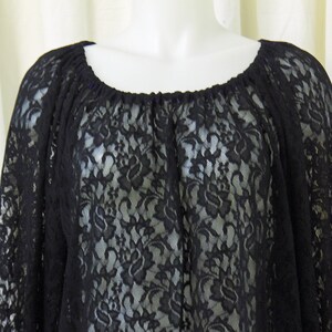 May include: Black lace top with a round neckline and long sleeves. The lace has a floral pattern.