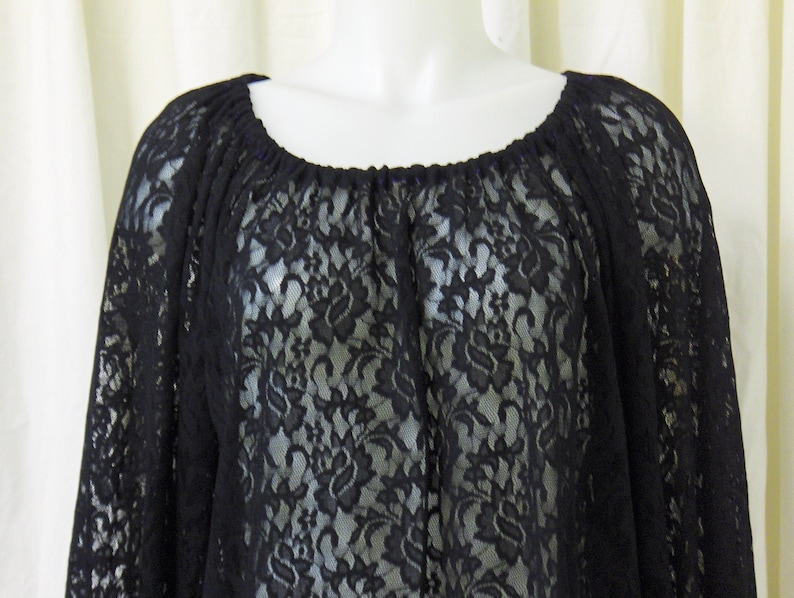 May include: Black lace top with a round neckline and long sleeves. The lace has a floral pattern.