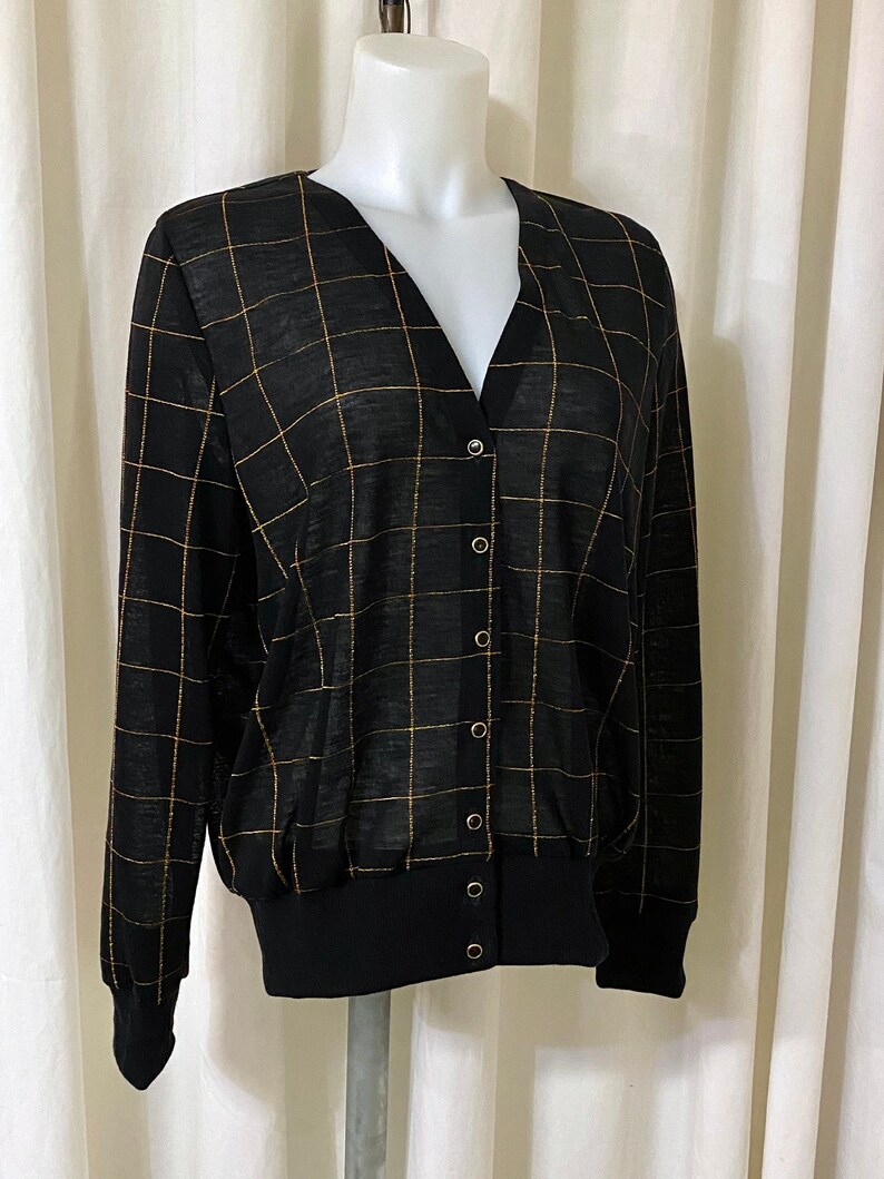 May include: Black and gold checkered cardigan with a v-neck and button closure.