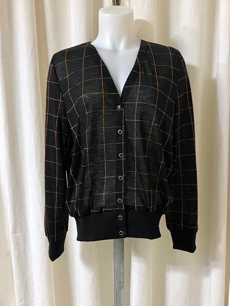 May include: Black and gold checkered cardigan with a v-neck and button closure.