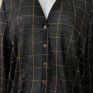 May include: A black long-sleeved button-up shirt with a gold grid pattern.