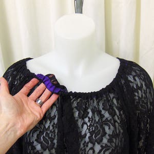 May include: Black lace top with a purple ribbon trim around the neckline.