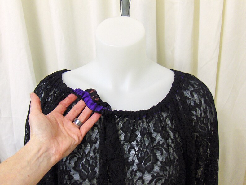 May include: Black lace top with a purple ribbon trim around the neckline.