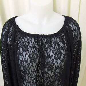 May include: Black lace top with a wide, gathered neckline. The top is sheer and has a delicate floral pattern.
