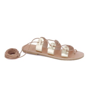 May include: Gold leather sandals with a lace-up design. The sandals have a flat sole and are tied around the ankle.