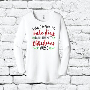 May include: White long-sleeved shirt with the text "I just want to bake stuff and listen to Christmas music" in red and green lettering.
