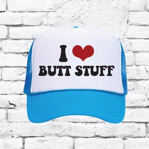 May include: A blue and white trucker hat with a red heart and the text "I ♥ BUTT STUFF" in black.