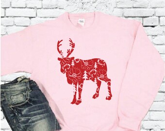 May include: A pink sweatshirt with a red reindeer silhouette. The reindeer is filled with a floral pattern.