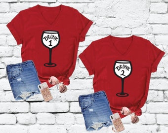 May include: Two red v-neck t-shirts with a white wine glass graphic and the text "Drunk 1" and "Drunk 2".