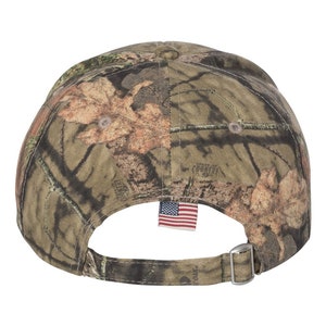 Puede incluir: Una gorra de b&eacute;isbol de camuflaje con una correa ajustable y una peque&ntilde;a bandera estadounidense cosida en la parte posterior.