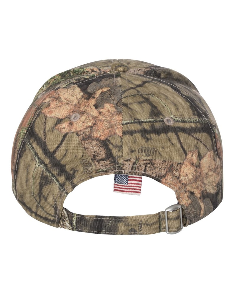 Puede incluir: Una gorra de b&eacute;isbol de camuflaje con una correa ajustable y una peque&ntilde;a bandera estadounidense cosida en la parte posterior.