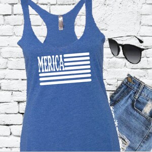 Puede incluir: Un top sin mangas azul con un gráfico blanco de la bandera estadounidense y la palabra "MERICA" impresa en él.
