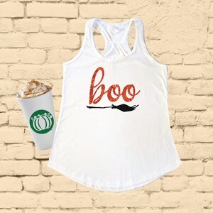 Pode incluir: Camisola branca de alças com um "boo" de glitter vermelho e uma silhueta preta de uma vassoura.