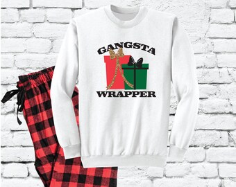 May include: White long-sleeved sweatshirt with the text "Gangsta Wrapper" and a graphic of two wrapped gifts with gold ribbon and bows. Matching red and black plaid pajama pants.