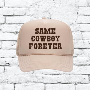 Può includere: Un cappello da camionista beige con testo marrone che recita "SAME COWBOY FOREVER".