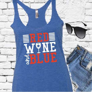 Puede incluir: Un top azul de tirantes con el texto "Red Wine and Blue" en letras blancas y rojas. La palabra "Wine" tiene una copa de vino tinto con una estrella blanca.