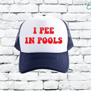 Puede incluir: Una gorra de camionero blanca y azul con una fuente retro roja que dice "I PEE IN POOLS" en la parte delantera.