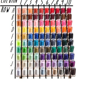 Puede incluir: Un gr&aacute;fico con filas etiquetadas de la A a la K y columnas etiquetadas del 1 al 10. Cada celda contiene un carrete de hilo de un color diferente.