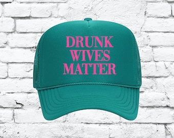 May include: A teal trucker hat with a pink embroidered message that reads "DRUNK WIVES MATTER".