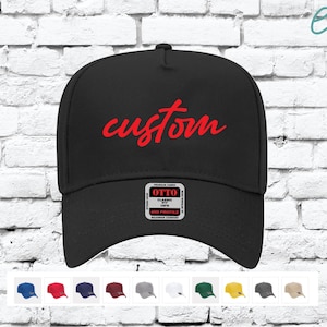 Könnte beinhalten: Schwarze Trucker-Kappe mit einem roten "custom" Stickerei auf der Vorderseite. Die Kappe hat ein mittleres Profil und eine klassische Passform.