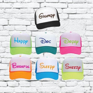 Puede incluir: Siete gorras de camionero diferentes con paneles traseros de malla blanca y paneles delanteros de colores. Las gorras presentan los nombres de los siete enanitos: Grumpy, Happy, Doc, Dopey, Bashful, Sleepy y Sneezy.