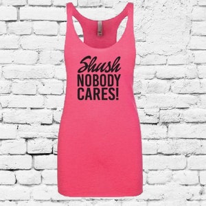 Puede incluir: Camiseta de tirantes rosa con un gráfico negro que dice "Shush Nobody Cares!"