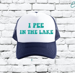 May include: A white and blue trucker hat with the text "I PEE IN THE LAKE" in teal.