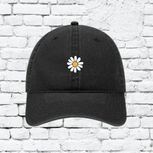 May include: A black baseball cap with a white daisy embroidered on the front.