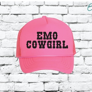 May include: Pink trucker hat with black mesh back and the text "EMO COWGIRL" in black block letters.