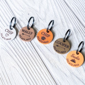 Puede incluir: Cinco etiquetas de perro de cuero personalizadas con diferentes dise&ntilde;os y nombres. Las etiquetas son de color marr&oacute;n, blanco y beige con letras negras. Los nombres en las etiquetas son Chip, Wally, Chip, Cooper y Sadie. Cada etiqueta tiene una fecha y un peque&ntilde;o dise&ntilde;o.