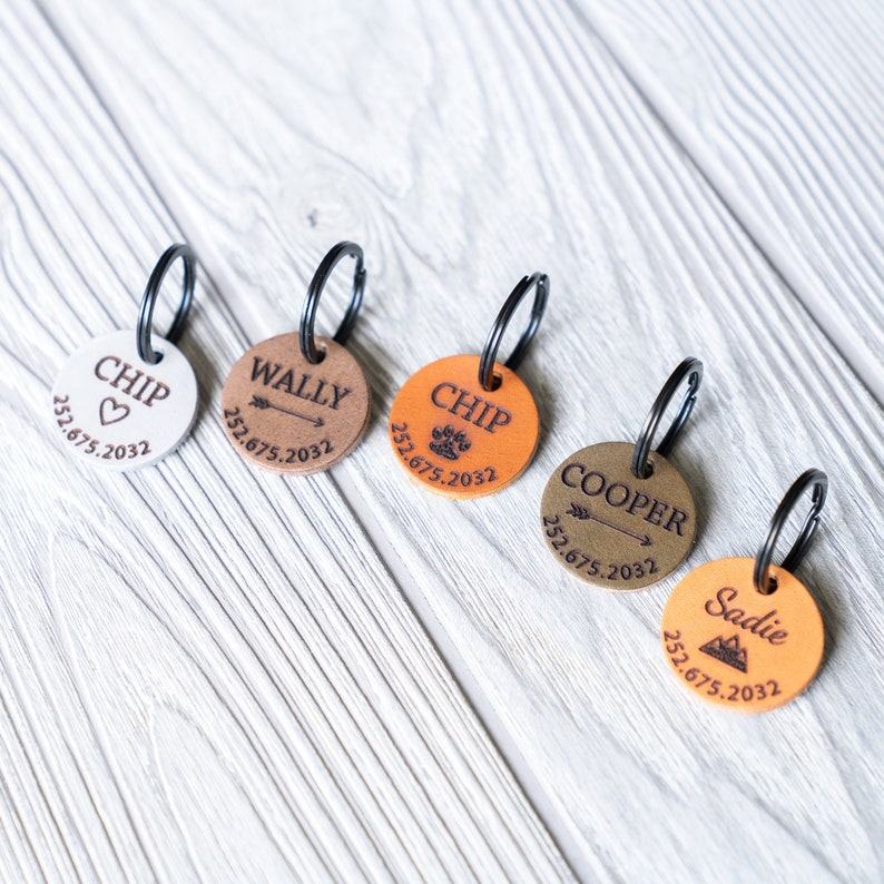 Puede incluir: Cinco etiquetas de perro de cuero personalizadas con diferentes dise&ntilde;os y nombres. Las etiquetas son de color marr&oacute;n, blanco y beige con letras negras. Los nombres en las etiquetas son Chip, Wally, Chip, Cooper y Sadie. Cada etiqueta tiene una fecha y un peque&ntilde;o dise&ntilde;o.