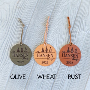 May include: Three leather Christmas ornaments in olive, wheat, and rust colors. Each ornament features a circle with three stylized Christmas trees and the text "The Hansen Family 2022".