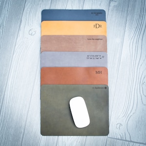 May include: A stack of six leather mousepads with different colors and personalized text. The top mousepad is dark blue with the text "XI.VILMMXV 8 FDR". The second mousepad is yellow with the text "Love thy neighbor.". The third mousepad is brown with the text "41° 2' 31.056" N 73° 54' 21.744" W ♡". The fourth mousepad is gray with the text "MH". The fifth mousepad is orange. The bottom mousepad is green with the text "A. Sanderson".