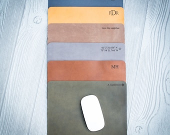 May include: A stack of six leather mousepads with different colors and personalized text. The top mousepad is dark blue with the text "XI.VILMMXV 8 FDR". The second mousepad is yellow with the text "Love thy neighbor.". The third mousepad is brown with the text "41° 2' 31.056" N 73° 54' 21.744" W ♡". The fourth mousepad is gray with the text "MH". The fifth mousepad is orange. The bottom mousepad is green with the text "A. Sanderson".