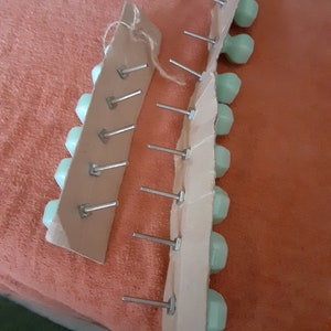 May include: Two packs of light green cabinet knobs with silver screws attached to brown cardboard backing.