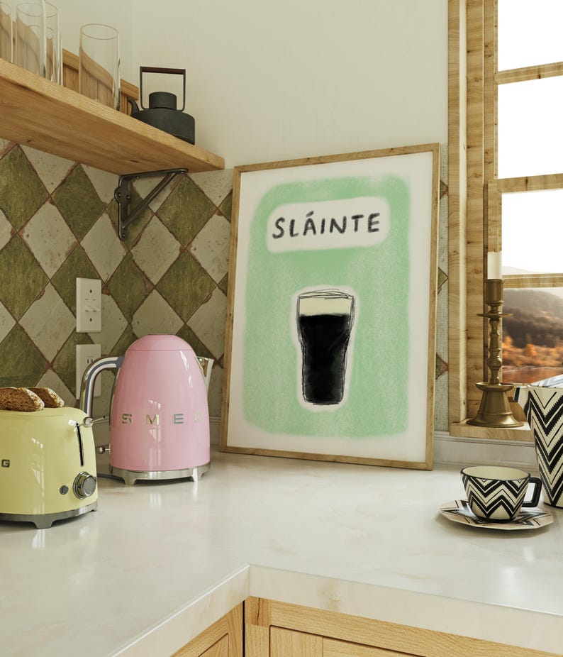 May include: A kitchen counter with a pink electric kettle, a yellow toaster, and a framed print with the word "Sl&aacute;inte" and a drawing of a glass of dark beer.