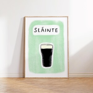 May include: A green and white poster with the word "Sl&aacute;inte" and a black and white illustration of a pint of beer.