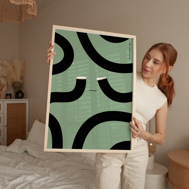 Girl holding up green guinness wall art poster retro vintage designof two wiggley guinness pints cheersing in the middle