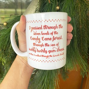 May include: White ceramic mug with a curved handle. The mug features red text that reads "I passed through the seven levels of the Candy Cane forest, through the sea of swirly twirly gum drops." Festive holiday theme.