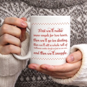May include: White ceramic mug with red text that reads "First we'll make snow angels for two hours, then we'll go ice skating, then we'll eat a whole roll of Tollhouse cookie dough as fast as we can, and then we'll snuggle." The mug is held by a person wearing a white sweater.