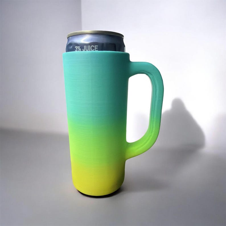 May include: A tall, gradient-colored mug in shades of teal, green, and yellow, with a handle. A beverage can with the text "3% JUICE" is inside the mug. The mug appears to be 3D-printed.