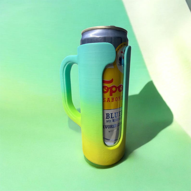 May include: A teal and yellow gradient can cooler with a handle, holding a can of Topo Chico Blue flavored sparkling water. The cooler is made of plastic and has a curved handle for easy gripping. The can is silver and yellow.