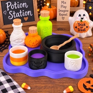 May include: A purple tray holding a black cauldron with a wooden spoon, a white mummy bottle, an orange pumpkin bottle, a green bottle, a candy corn cup, a black bat cup, and a white ghost cup, all featuring Halloween-themed designs.