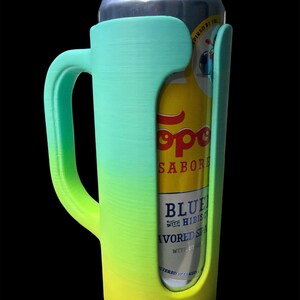 May include: A gradient green and yellow can cooler with a handle, holding a can of Topo Chico sparkling water. The cooler is designed to fit a standard-sized can and features a handle for easy carrying.