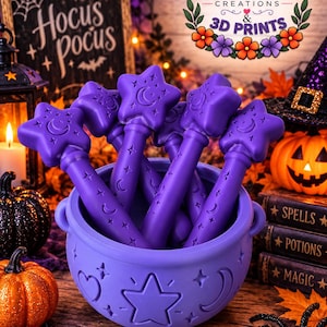 May include: A purple cauldron with a star and moon motif containing several matching purple wands, each topped with a star and moon design. The cauldron and wands feature embossed celestial patterns including stars and crescent moons.