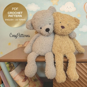 May include: Two plush teddy bears, one gray and one tan, sit side-by-side on a wooden surface. The gray bear has a black nose and the tan bear has a brown nose. The background features a whimsical design with clouds, stars, and a hot air balloon. The image includes text that says "PDF CROCHET PATTERN ENGLISH - US TERMS" and "CosyPatterns".
