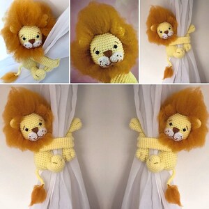 May include: Two crocheted lion curtain tiebacks in yellow and orange. The lions are holding onto white curtains with their paws.