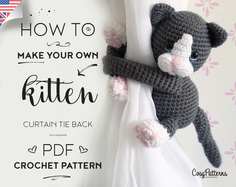 May include: A crochet pattern for a gray and white kitten curtain tie back. The pattern is available as a PDF download. The image shows a finished kitten tie back holding a curtain.