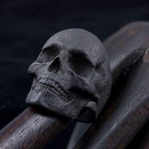 gothic blackened steel skull ring on wooden carved hand